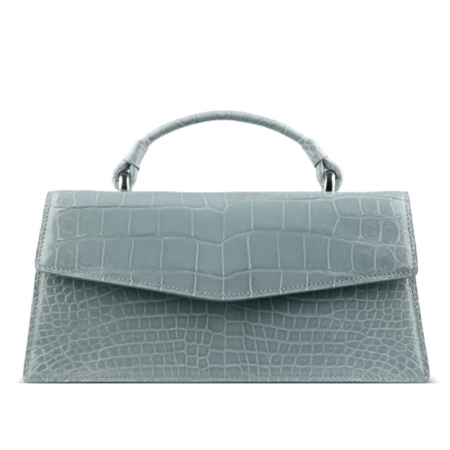 Light blue handbag with a crocodile-textured surface and a short curved handle against a white background.